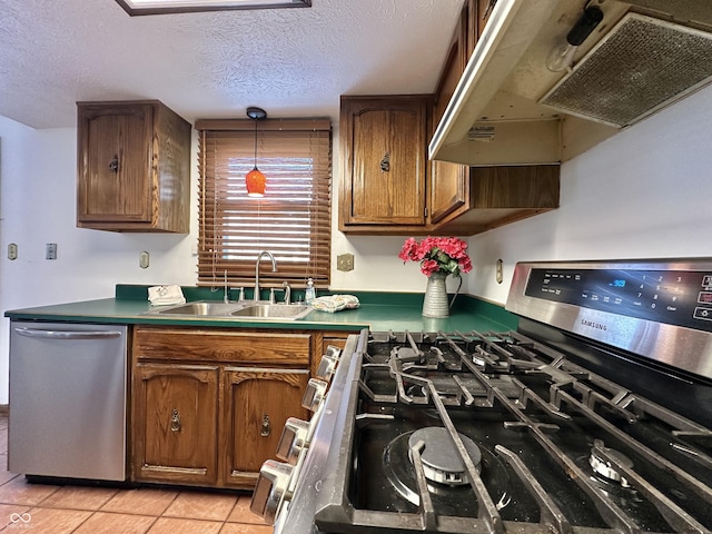 kitchen with light tile patterned floors, brown cabinetry, a sink, under cabinet range hood, and appliances with stainless steel finishes