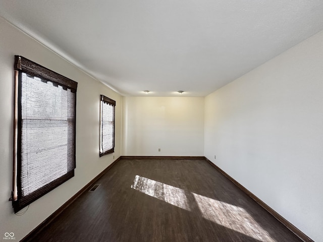 spare room featuring visible vents, baseboards, and wood finished floors