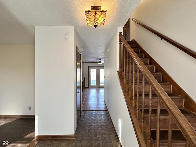 stairs featuring french doors, baseboards, a textured ceiling, and ceiling fan