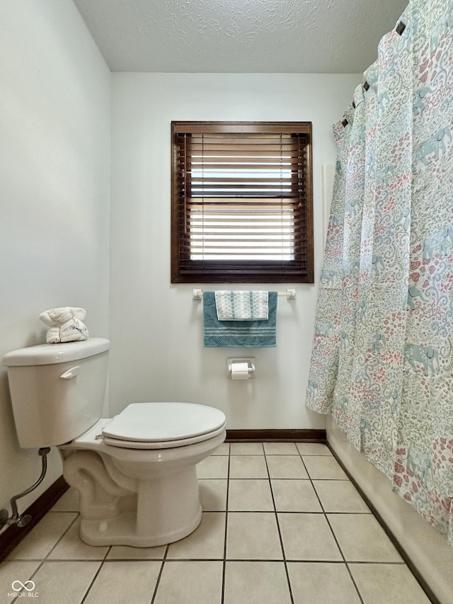 bathroom with baseboards, tile patterned flooring, shower / bath combo with shower curtain, a textured ceiling, and toilet