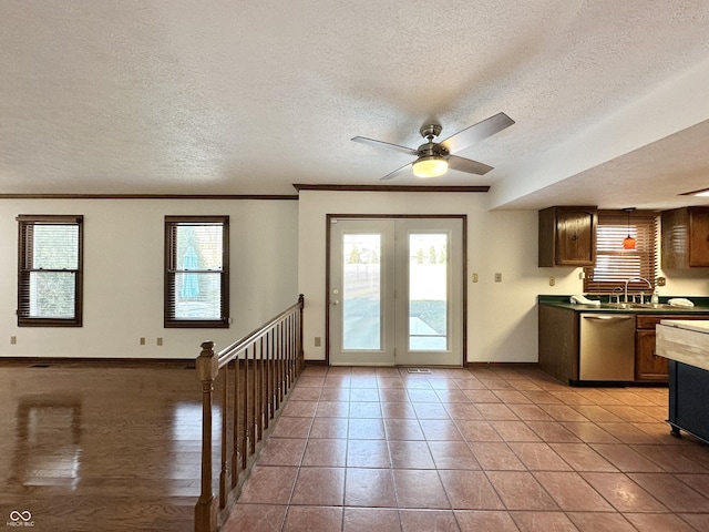 kitchen with a ceiling fan, a textured ceiling, crown molding, baseboards, and dishwasher