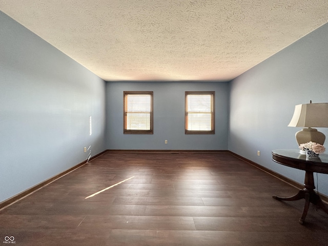 unfurnished room with wood finished floors, baseboards, and a textured ceiling