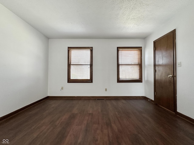 unfurnished room featuring dark wood finished floors, baseboards, and a textured ceiling