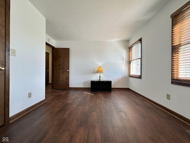 unfurnished room featuring baseboards, a textured ceiling, and wood finished floors