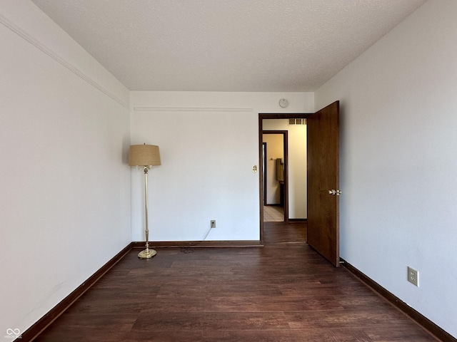 unfurnished room with visible vents, dark wood-style floors, baseboards, and a textured ceiling