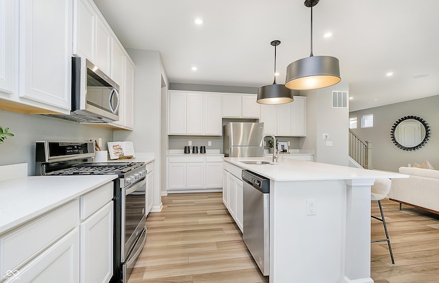 kitchen featuring a kitchen breakfast bar, light wood-style floors, visible vents, and stainless steel appliances