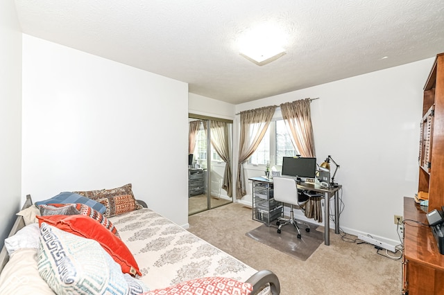 bedroom featuring a closet, light colored carpet, a textured ceiling, and baseboards