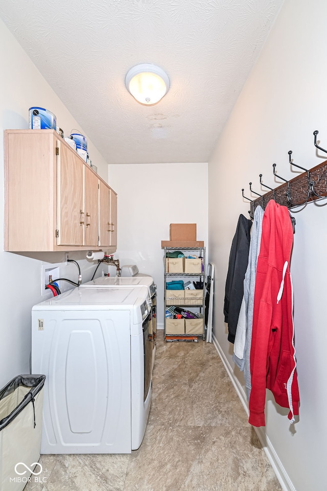 clothes washing area with a textured ceiling, cabinet space, independent washer and dryer, and baseboards