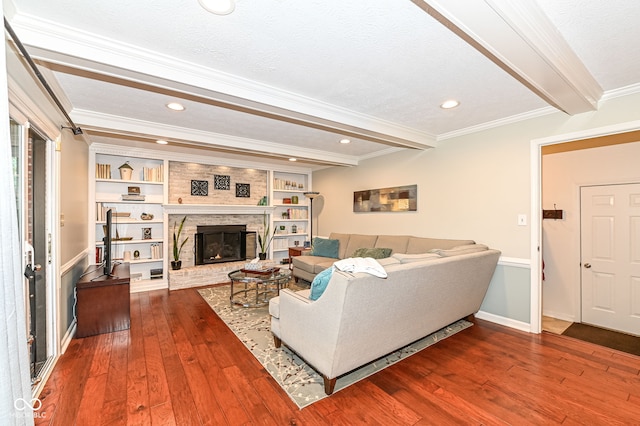 living area with beam ceiling, ornamental molding, hardwood / wood-style floors, recessed lighting, and a large fireplace