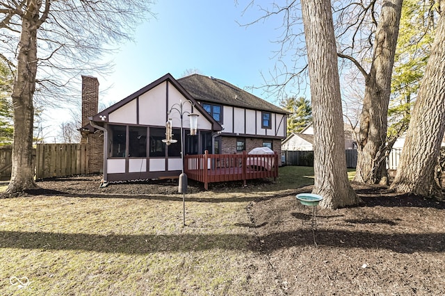 back of house featuring fence, a wooden deck, a sunroom, stucco siding, and a chimney