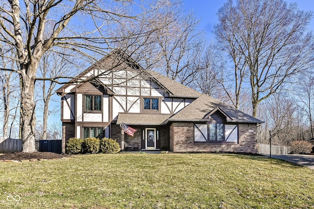 tudor house with brick siding, a front lawn, and fence