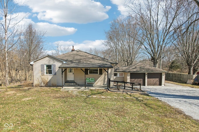 view of front facade featuring an outbuilding, a front lawn, a detached garage, fence, and a shingled roof