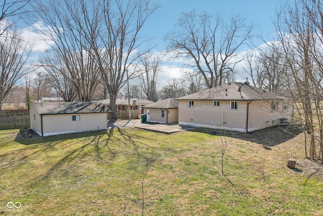 back of property with an outbuilding, a yard, fence, and a patio area