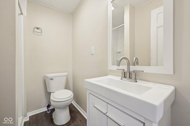 bathroom featuring baseboards, toilet, wood finished floors, and vanity