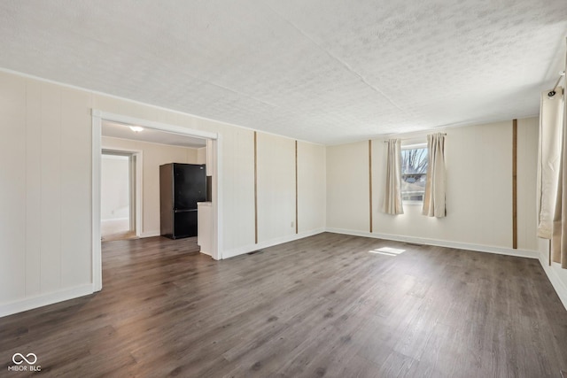 empty room featuring dark wood-type flooring, baseboards, visible vents, and a textured ceiling