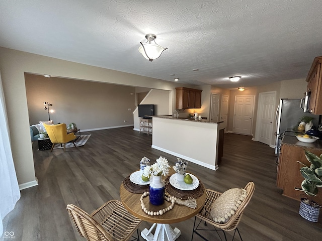 dining space featuring dark wood finished floors, baseboards, and a textured ceiling