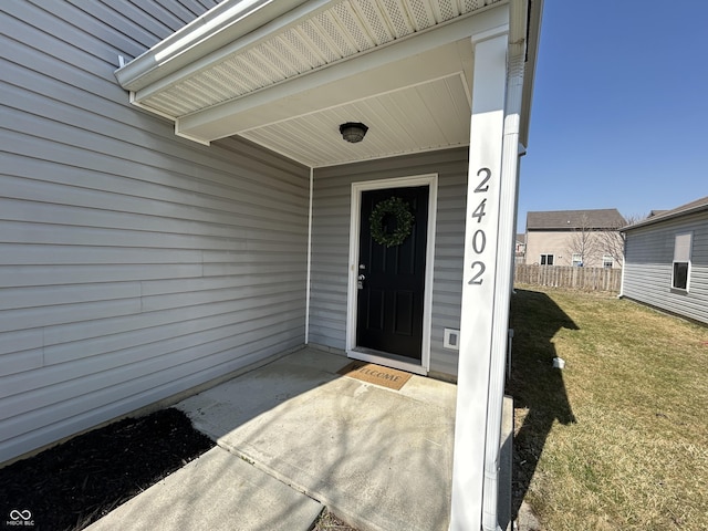 doorway to property with a lawn and fence