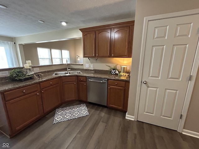 kitchen with a healthy amount of sunlight, dark wood finished floors, a sink, a textured ceiling, and stainless steel dishwasher