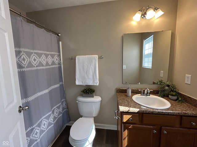 bathroom with curtained shower, baseboards, toilet, wood finished floors, and vanity