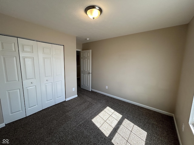 unfurnished bedroom with a closet, baseboards, and dark colored carpet