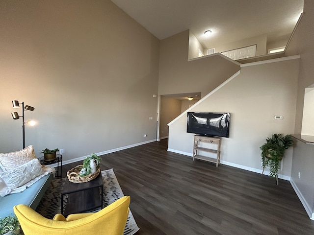 living area featuring visible vents, baseboards, a high ceiling, and wood finished floors