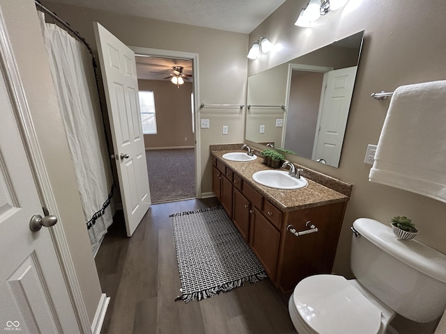 full bath featuring double vanity, toilet, a ceiling fan, and a sink