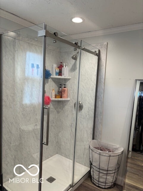 bathroom featuring a stall shower, wood finished floors, and ornamental molding