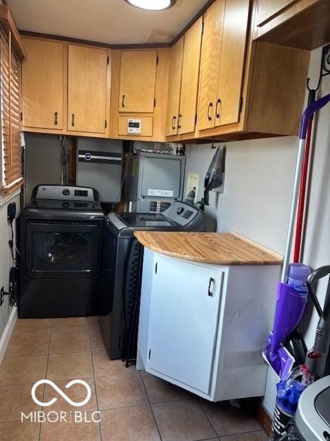 clothes washing area with light tile patterned floors, cabinet space, and washing machine and clothes dryer