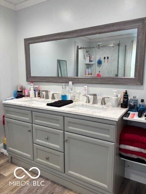 bathroom featuring a sink, wood finished floors, ornamental molding, and double vanity