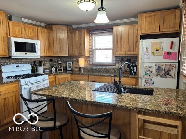 kitchen featuring backsplash, white appliances, a breakfast bar, and a sink