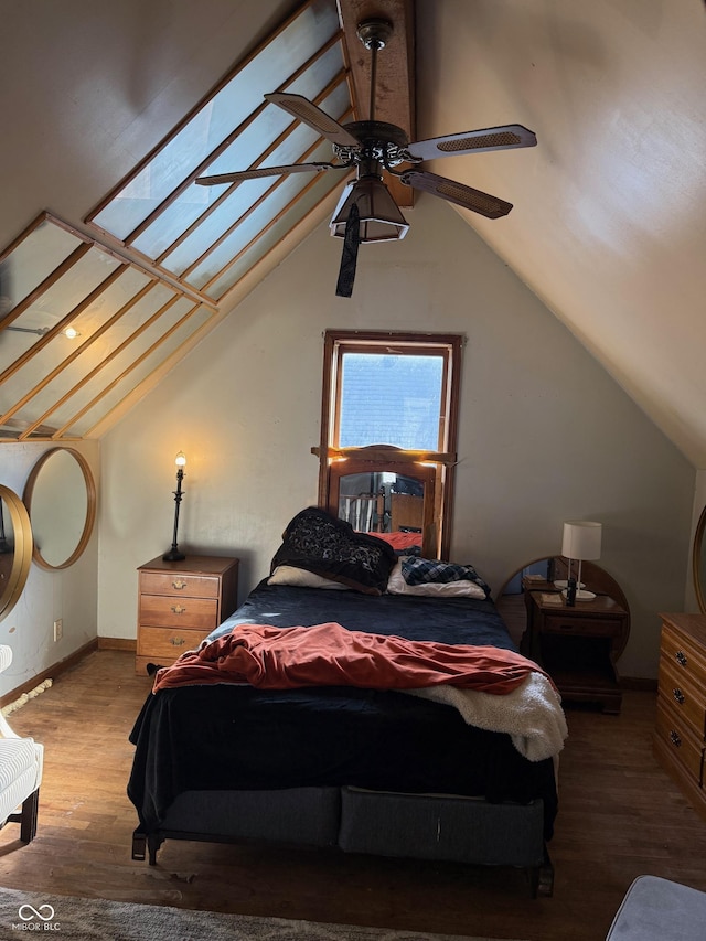 bedroom featuring vaulted ceiling with skylight, wood finished floors, baseboards, and ceiling fan