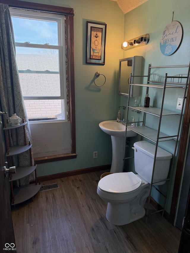 half bathroom with baseboards, toilet, wood finished floors, and vaulted ceiling