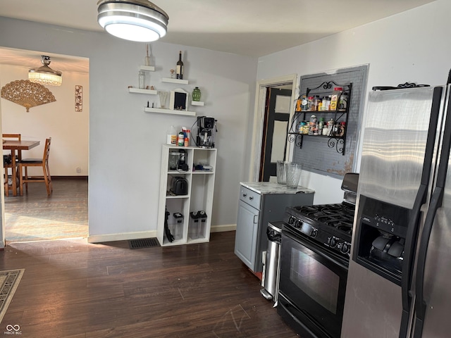 kitchen with baseboards, black gas range oven, dark wood-style floors, and stainless steel fridge with ice dispenser