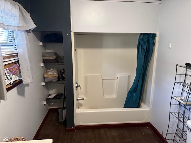 bathroom featuring shower / tub combo, wood finished floors, and baseboards