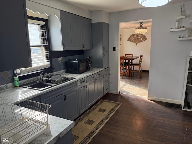 kitchen with light countertops, dark wood-style floors, black microwave, and a sink