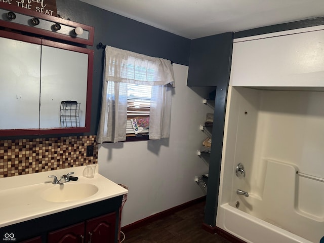 full bath featuring vanity, wood finished floors, baseboards, tub / shower combination, and backsplash