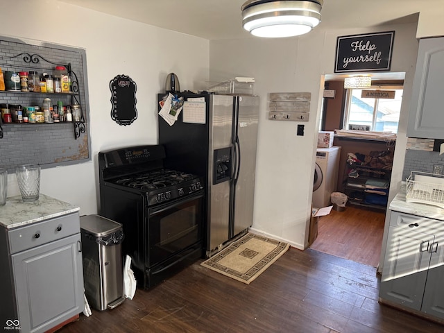 kitchen featuring dark wood finished floors, washer / dryer, gas stove, and stainless steel fridge