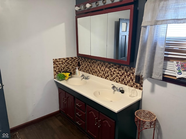 bathroom with wood finished floors, baseboards, backsplash, and a sink