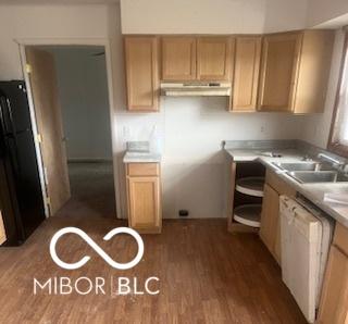 kitchen featuring under cabinet range hood, freestanding refrigerator, wood finished floors, white dishwasher, and a sink