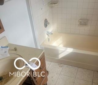 full bath featuring washtub / shower combination and tile patterned flooring