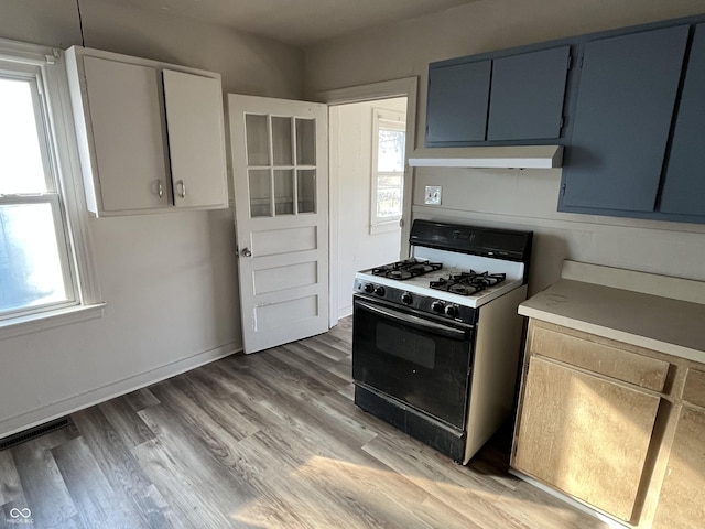 kitchen with under cabinet range hood, visible vents, range with gas cooktop, and a wealth of natural light