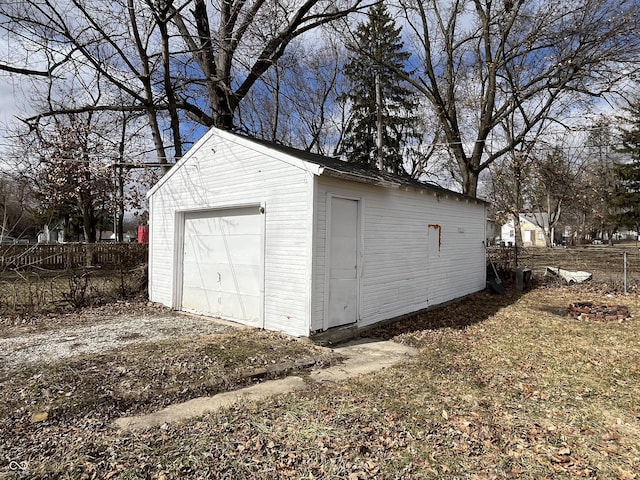 detached garage featuring fence and dirt driveway