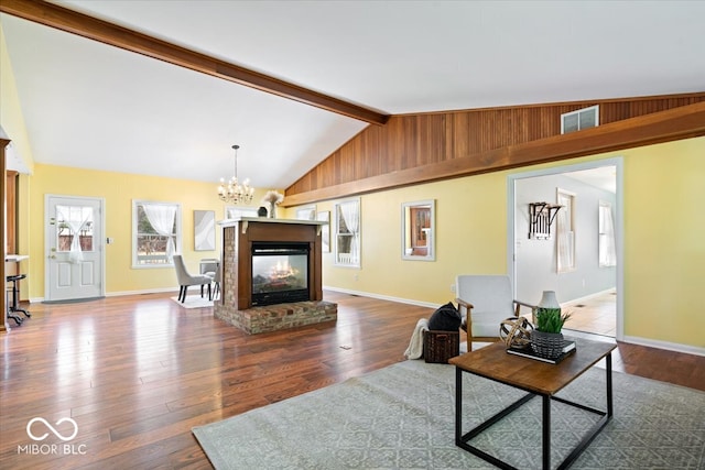 living area featuring visible vents, vaulted ceiling with beams, baseboards, an inviting chandelier, and wood-type flooring