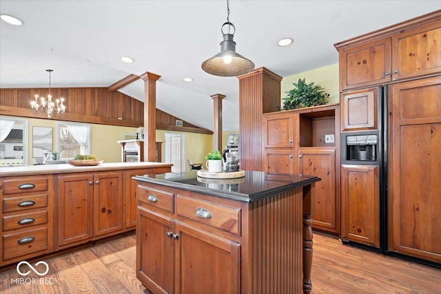 kitchen featuring lofted ceiling, light wood-style flooring, brown cabinetry, and hanging light fixtures