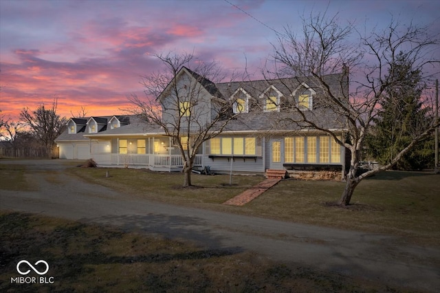 cape cod house with a front yard, a garage, covered porch, and dirt driveway