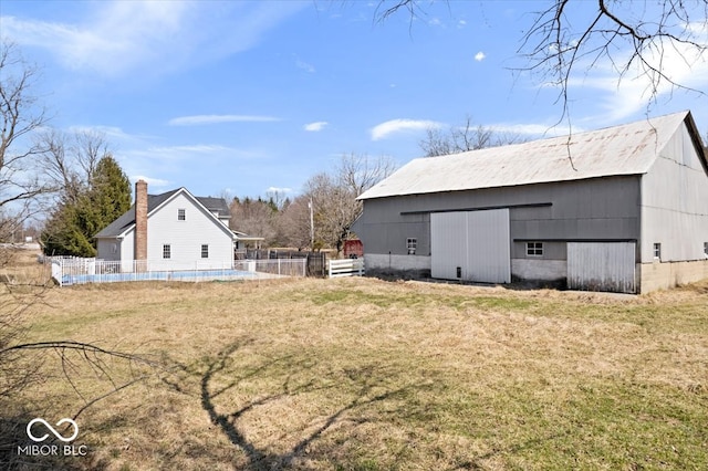 view of yard featuring an outbuilding, a fenced in pool, an outdoor structure, and fence