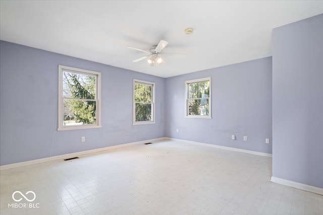 spare room featuring tile patterned floors, visible vents, baseboards, and ceiling fan