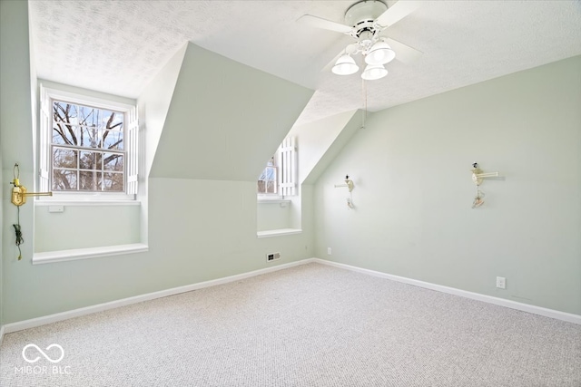 bonus room featuring lofted ceiling, a textured ceiling, carpet flooring, baseboards, and ceiling fan