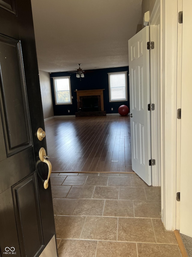 interior space featuring baseboards, plenty of natural light, ceiling fan, and a fireplace