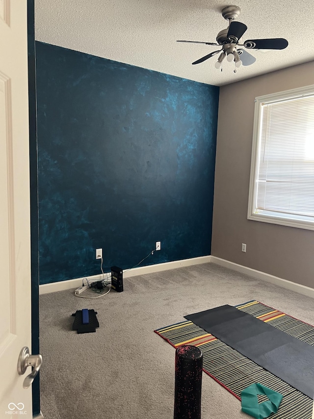 unfurnished room with baseboards, carpet, a ceiling fan, and a textured ceiling